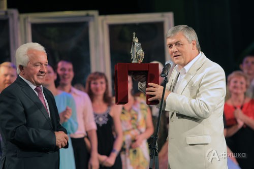 Мэр города Белгорода Сергей Боженов вручает юбиляру статуэтку с симовлом города